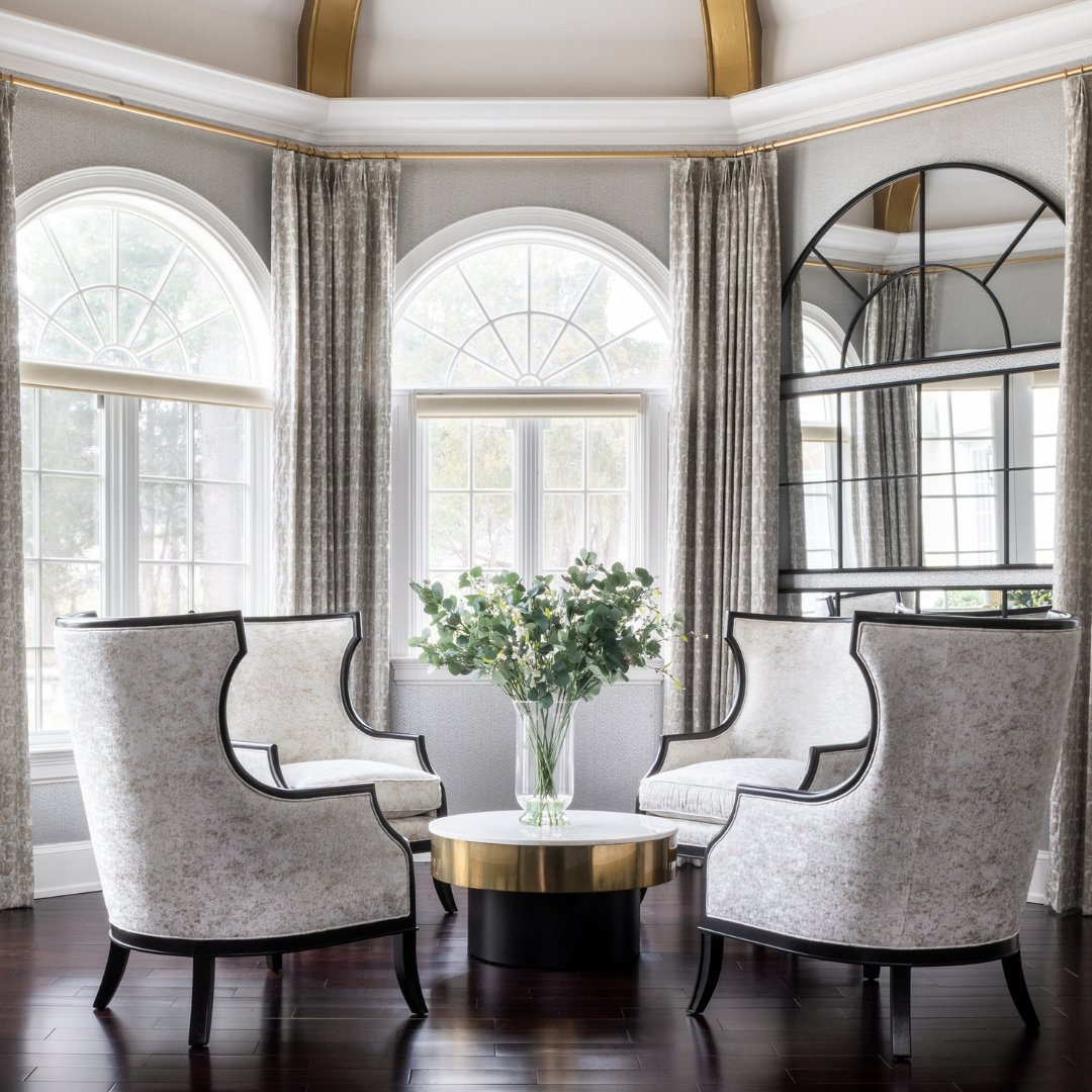 Designed for effortless entertaining, this elegant sitting area blends contrast, texture, and craftsmanship. Dark wood elements paired with neutral upholstery create a sophisticated foundation, while tailored stationary drapery panels introduce timeless refinement. Gold...
