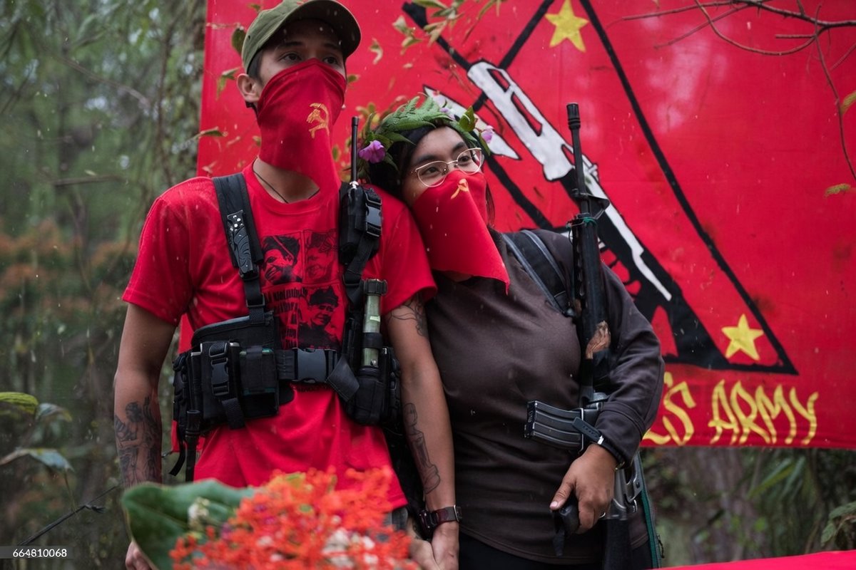 A communist couple raising their fists while reciting their vows during a simple wedding ceremony held at a guerrilla camp in the remote hinterlands of Mountain Province, Philippines.