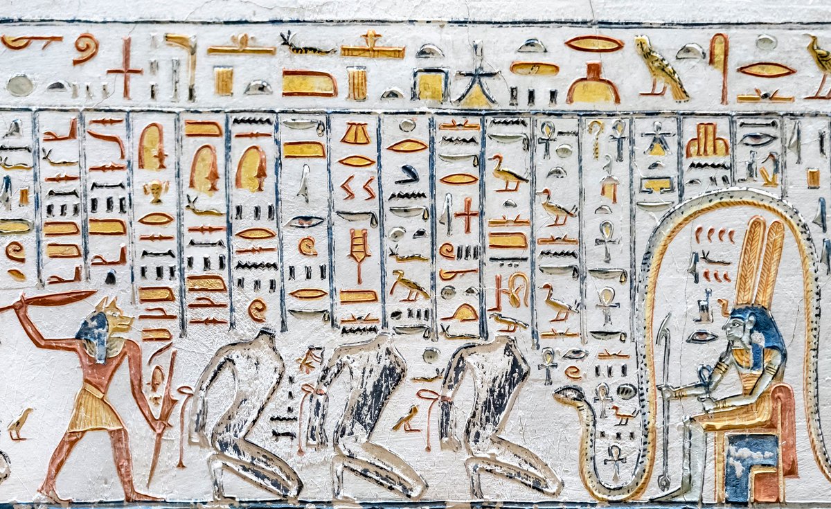 egyptomuseum's tweet photo. Headless Bound Figures from the Fifth Hour of the Amduat

New Kingdom, 20th Dynasty, c. c. 1150–1130 B.C.

Tomb of Ramesses V–VI, Valley of the Kings, Thebes

▫ This scene, carved on the right wall of Corridor G in KV9, belongs to the Fifth Hour of the Imydwat (Amduat), The Book of What Is in the Netherworld, a royal funerary composition describing the sun-god Ra’s nocturnal journey through the Duat.

At centre are three headless, black-painted, bound figures kneeling in submission, beings identified as the enemies of Ra and Osiris, embodiments of chaos who have rebelled against Maʿat (cosmic order). Their decapitation signifies complete annihilation; the destruction of identity, voice, and the possibility of rebirth.

Before them stands a knife-bearing, jackal-headed underworld guardian, poised to strike; an executioner of Sokar–Osiris and destroyer of the enemies of Ra, who enforces divine justice through ritualised annihilation rather than arbitrary violence.

To the right, an enthroned, green-skinned mummiform god wearing the double plumes (a Sokar–Osiris form) presides within his sacred domain, marking this punishment as a sanctioned act within the hidden necropolis of the underworld.

The Fifth Hour represents one of the most inert and dangerous regions of the Duat, where hostile forces must be neutralised so that Ra’s solar barque may continue its passage toward renewal.

For the deceased king, the scene affirms his alignment with divine order and his safe inclusion among the justified, while proclaiming a central Egyptian belief, of which chaos is contained, justice is active, and rebirth is assured.