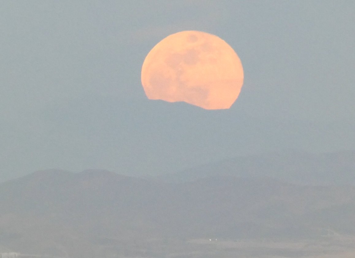 The February Full (Snow) Moon making its appearance in a hazy sky as seen from across the Las Vegas Valley.