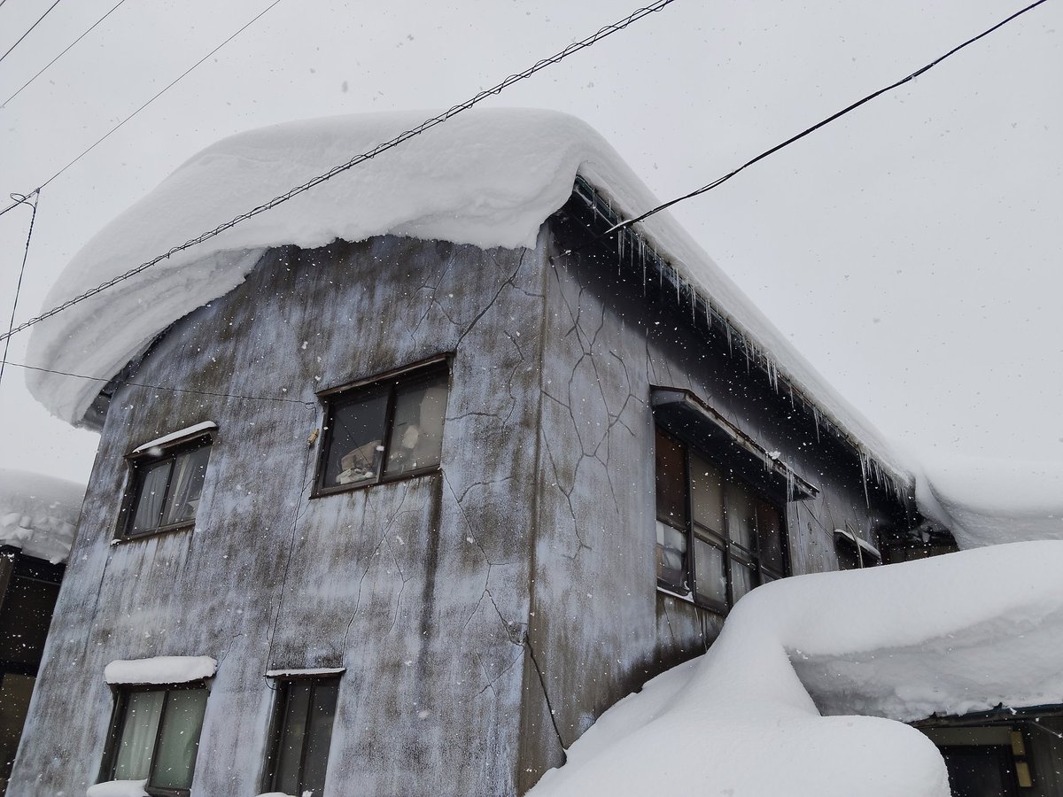 大館市内のこの冬にまだ一度も雪下ろしをしていない屋根では、今現在このような1メートル以上もあろうかという雪が重く固まった状態で見られます。そして、恐ろしいことに明日は気温が上がって雨予報です。こんな雪が崩れて一気に落ちてくれば、建物被害や人的被害も起きかねないと心配しております。