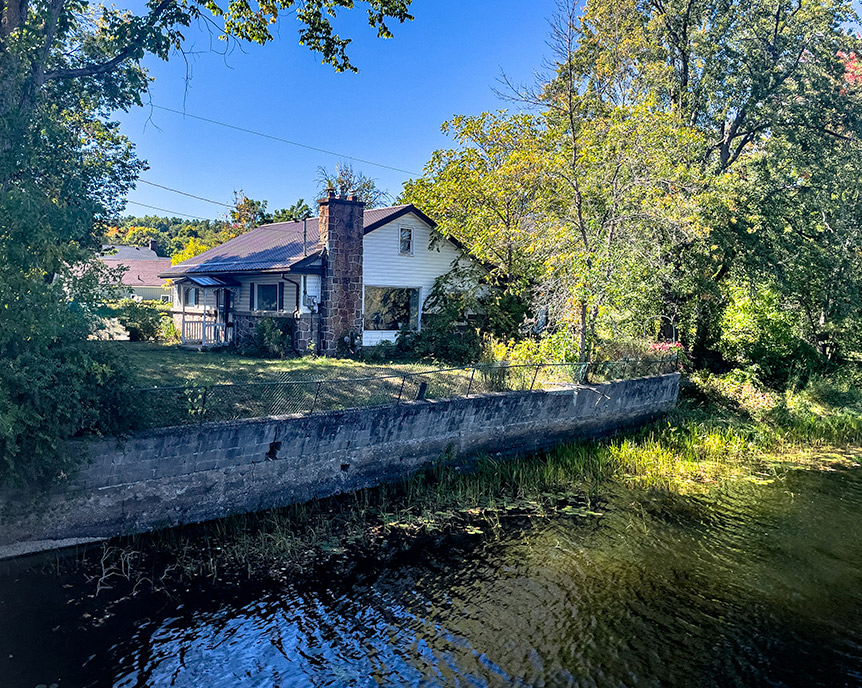 DaveToshTosh's tweet photo. Mid Century Modern bungalow, vinyl exterior with decorative stone, steel roof &amp; rubber membrane over the single attached garage. Large kitchen and Sunroom. 134 feet of riverfront on the Moira, next to the Pedestrian Bridge. https://t.co/i2mux0WzZQ
