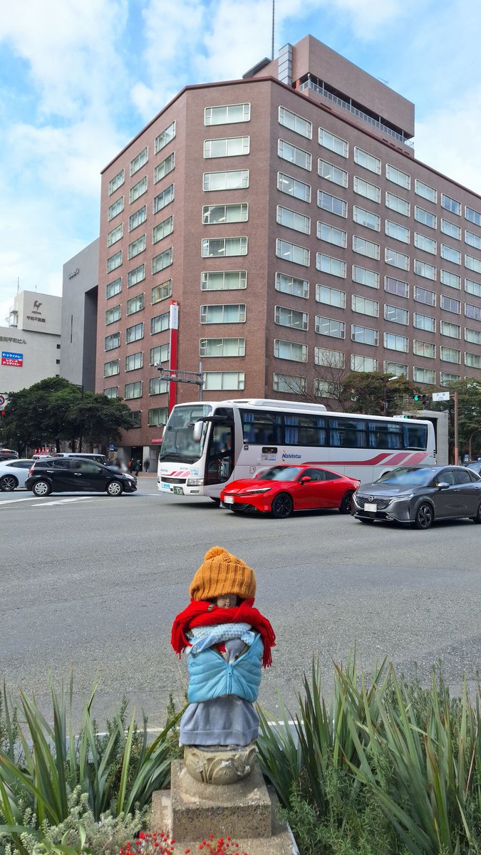 久々の #天神地蔵
過去に二度破損被害に遭い、ワンビル建設の歩道整備nなどで一時的に立ち退き？されたが、再び戻って来て１年…。
天神ビルやバスとの風景、50年近くになります。