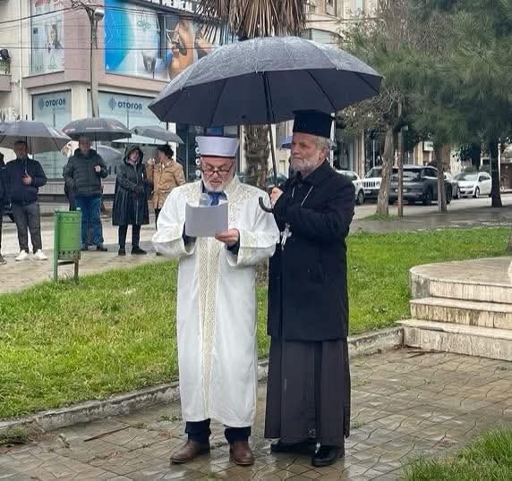 Arnavutluk'ta bir rahip, konuşma yapan imam konuşmasını bitirene kadar şemsiye ile onu yağmurdan korudu.