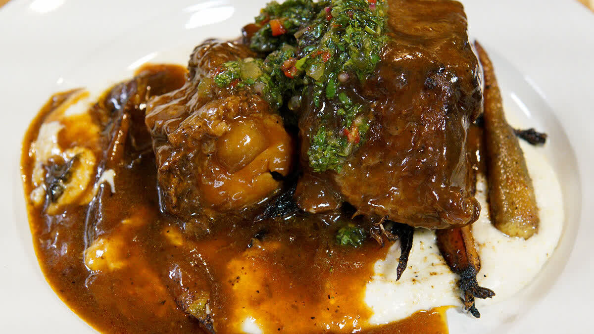 RobertIrvine's tweet photo. Short ribs have a lot of collagen and connective tissue, but when cooked low and slow (about 4 hours), that collagen melts into gelatin, giving you nothing but savory, tender meat and a rich braising liquid. The peaches add a distinct sweetness that's balanced perfectly by the creamy grits. Enjoy! 

PEACH BBQ SHORT RIBS

YOU'LL NEED
FOR THE GRITS
2 cups milk
1 cup water
1 cup grits
½ cup cream cheese
2 oz cheddar cheese, shredded
1 stick butter
Salt and pepper, to taste

FOR THE VEGGIES
3 tbsp grapeseed oil
20 baby carrots, cut in half
1 white onion sliced
4 cloves garlic, sliced
Salt and pepper, to taste

MAKE IT

SHORT RIBS
1) Pre-heat oven to 325.
2) Season the short ribs liberally with salt and pepper.
3) In a roasting pan over medium-high heat, add grapeseed oil and short ribs. Sear short ribs on all sides and remove from the pan.
4) Add carrots, celery, and onions. Lightly sear. The veggies should be light brown in color.
5) Add peaches and allow to cook for approximately 2 minutes.
6) Deglaze the pan with white wine and allow to reduce. Add chicken stock, beef stock, and thyme. Add the short ribs back to the pan and cover.
7) Place the rib braise into the oven and cook for about 4 hours.
8) Pull short ribs from the oven and allow to cool in the braise.
9) Using a ladle remove 1 qt of the braising liquid and place in a separate pan. Set the liquid aside. This will be the sauce for the braised short ribs.

HERB SALAD
1) In a mixing bowl add parsley, cilantro, and shallots.
2) Add extra virgin olive oil and lemon juice.
3) Season with salt and pepper.

GRITS
1) In a saucepan add milk and water. Bring to a boil.
2) Using a whisk incorporate grits.
3) Drop temperature to a low simmer and cook for about 12 minutes, stirring occasionally.
4) Add cream cheese, cheddar cheese, and butter. Season and set aside.

VEGGIES
1) In a sauté pan over medium-high heat, add grapeseed oil and carrots.
2) Sear carrots for about 3 minutes, then add onions and garlic.
3) Lower the heat to medium-low and cover. Cook for about 4 minutes, stirring occasionally.

PLATING
1) Place a scoop of grits in the middle of the plate.
2) Top the grits with the carrot and onion mixture.
3) Place braised short rib on top of the carrots.
4) Top the short rib with the braising liquid that was previously set aside.
5) Finish with the chopped herb salad.