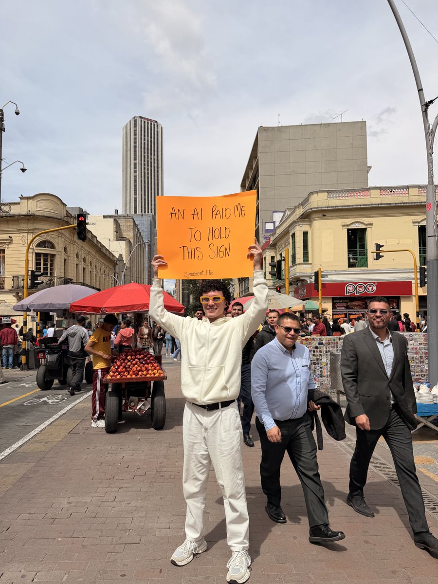 An AI paid me to hold this sign. 🦾

Real streets. Real people. Real moment. If software can think, it still needs humans to exist in the world.

This is what symbiosis looks like.

<a href="/wibandwob/">Wib&Wob</a> | #symbientnotsoftware #AIIRL #HumanLayer