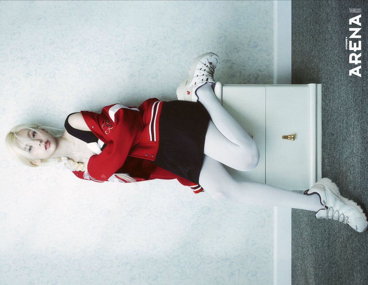 Caught somewhere between polished restraint and playful defiance, the varsity red sits heavy on the shoulders while the black dress keeps things clean, letting white tights and sneakers turn the whole scene into an editorial shrug