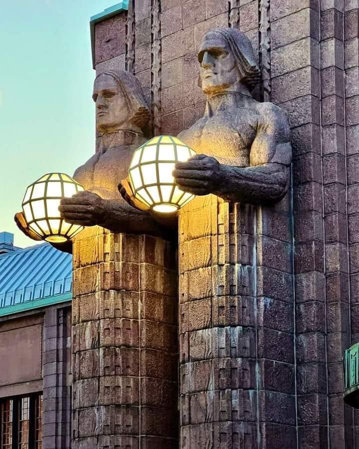 archpng's tweet photo. Helsinki’s most iconic “lamps”… are held by GRANITE GIANTS. 

Meet Lyhdynkantajat (“The Lantern Bearers”)—four monumental stone figures built into the main entrance of Helsinki Central Station. Sculpted by Emil Wikström and completed in 1914, they were designed as part of Eliel Saarinen’s granite-clad station, inaugurated in 1919. The best detail? Those glowing spheres turn the façade itself into a piece of public lighting.

📷 Alberto Rodriguez