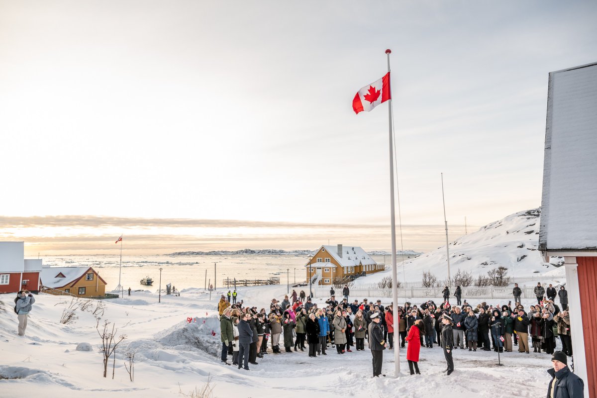 Une foule observe la ministre Anand hisser le drapeau canadien devant le nouveau consulat du Canada à Nuuk, au Groenland, par une journée d'hiver ensoleillée.