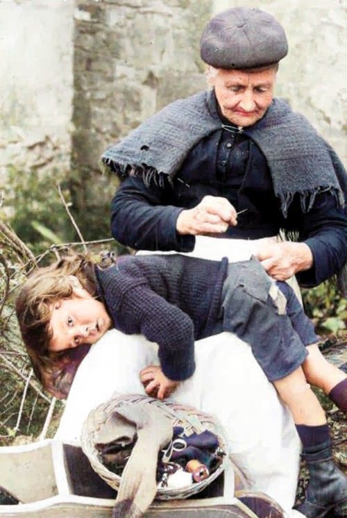 A Cornish grandmother mending her grandson's shorts in 1907.