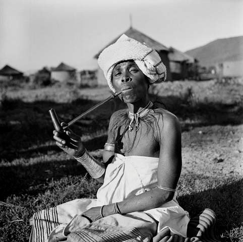 Xhosa woman smokes a pipe outside in a rural village in Transkei, South Africa. Photo: Anne Fischer Photographic Collection