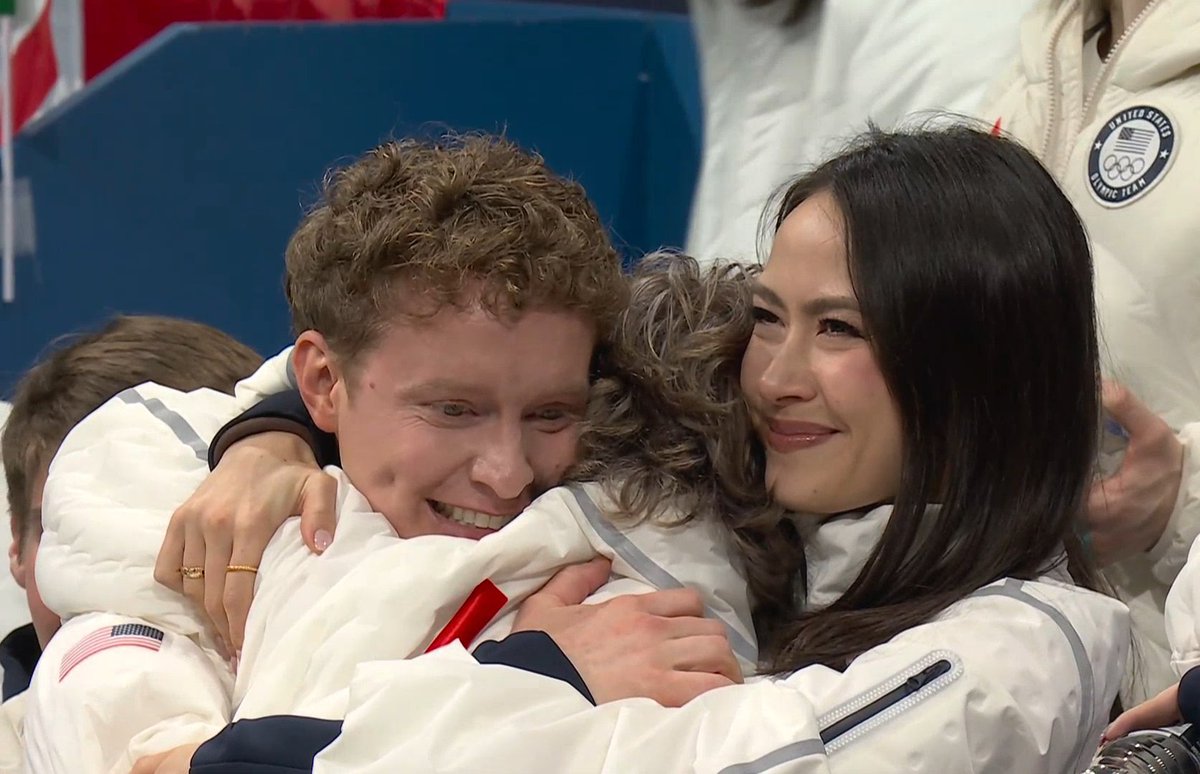 Ilia Malinin hugging Madison Chock and Evan Bates after winning the team event gold medal at the 2026 Olympic Winter Games!