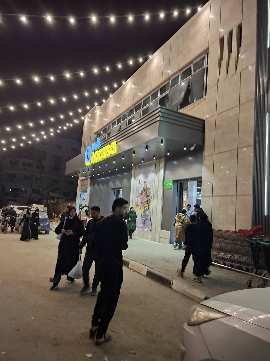 KhaledSafi's tweet photo. نعم.. هذا المول يقع في قطاع غزة، وتحديدًا في منطقة السرايا وسط المدينة..
وتم بناؤه مثل كثير من المطاعم والمقاهي التي أعيد افتتاحها من جديد.
لكن قبل أي تعليق متسرّع، دعونا نتفق على حقيقة أساسية: واقع غزة معقّد، ولا يُقرأ من صورة واحدة ولا يُختزل في مشهد واحد.
يمكنك أن تنظر إلى المشهد من زاويةٍ ما، فتراه تعبيرًا عن قدرة أهل غزة على التعافي، وعن إصرارهم على الحياة، ومحاولتهم النهوض من تحت الركام؛ وهو ما يغيظ المحتل المجرم ويُفشل، ولو جزئيًا، مشروع التهجير الذي لا يغادر غرف قراره.

لكن هذه الزاوية، مهما بدت مشرقة، لا تلغي الواقع الأليم، ولا تنفي حجم الاحتياج الكاسح الذي يعانيه السواد الأعظم من سكان القطاع، في ظل شحّ الموارد، وانقطاع الكهرباء، وانهيار مقومات الحياة الأساسية.

نعم، هناك من يحاول..
لكنهم بحاجة، وما زالت المعاناة هي القاعدة لا الاستثناء.
فإن كانت مثل هذه الأخبار كفيلة بتغيير قناعتك أو إعادة توجيه موقفك من غزة، فربما المشكلة ليست في غزة، بل في ضيق زاوية النظر.
غزة لا تُفهم باللقطات، بل بالقراءة العميقة، وبالاطلاع على تفاصيل معقّدة ومتشابكة لا تظهر في العناوين السطحية.
