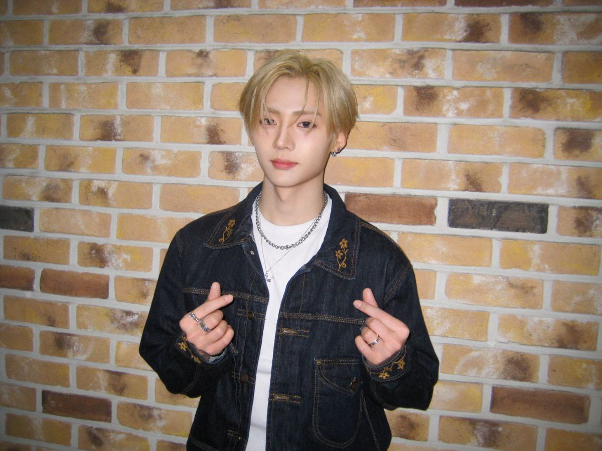 ᅠ
Honey-blond halo against sun-warmed brick, denim stitched with quiet florals—silver rings glint as he sends twin heartbeats into the air; soft yet steadfast, a golden hour wrapped in indigo ease.
ᅠ