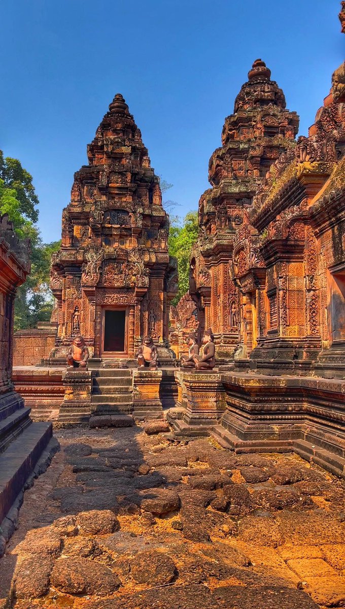 Golden sunlight kisses the intricate carvings of Banteay Srei, a true masterpiece of ancient Khmer artistry. 

Every detail in this sacred sanctuary, nestled within the historic Angkor Archaeological Park, tells a story carved in stone. The warm tones, the guardian statues, and