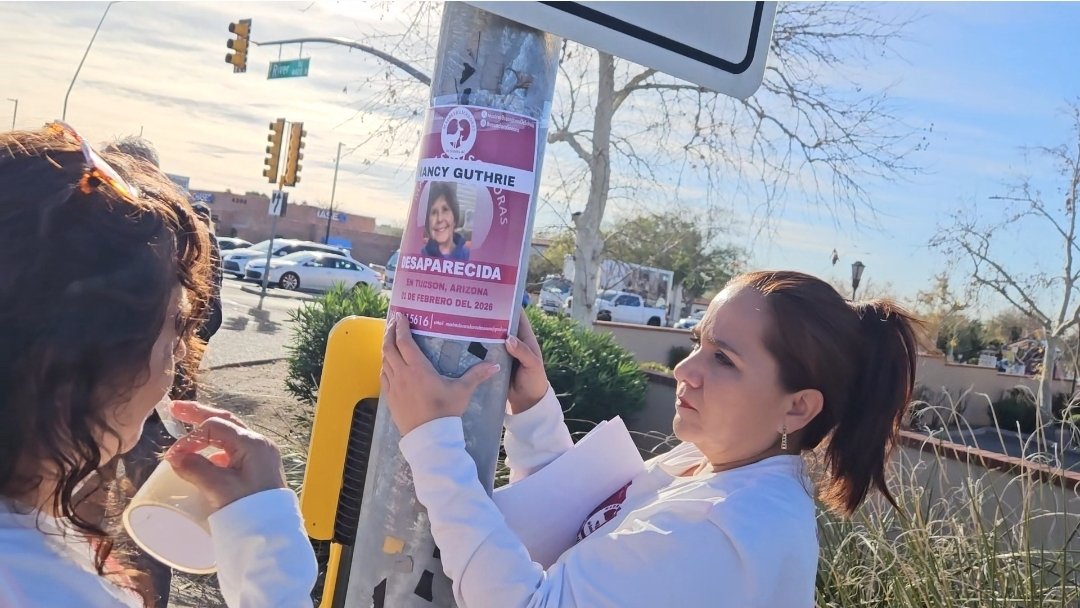 Group of women posting Nancy Guthrie missing flyers on poles at Campbell &amp; River Rd.