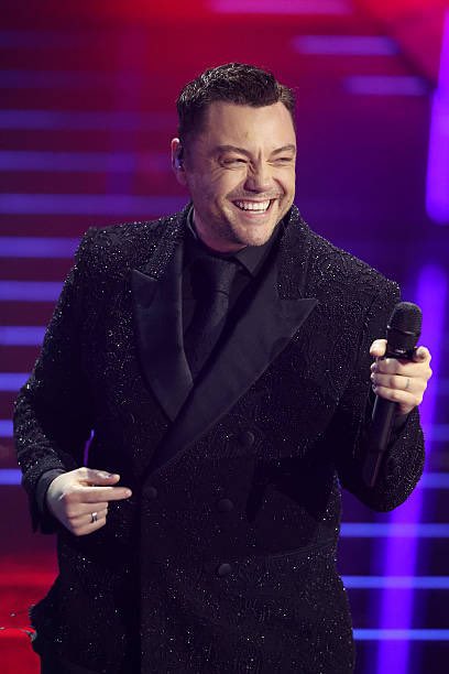 MarioManca's tweet photo. C’è sempre un momento a Sanremo in cui arriva un ospite che canta le canzoni che ci hanno accompagnato per una vita e noi, che siamo cresciuti a pane e nostalgia, non possiamo fare a meno di urlarle dal divano ricordandoci com’eravamo «quando si potevano mangiare anche le fragole». Tiziano Ferro sa bene di avere un repertorio forte, ed è per questo che ogni volta che sale su quel palco sa che, se semmai dovesse dimenticarsi le parole, ci sarebbe sempre il pubblico da casa e a teatro a cantarle per lui. Non c’è nulla di più sanremese di quel rito di radunarsi davanti alla televisione e abbracciarsi per cantare a squarciagola successi come «Perdono», e su questo non ci piove ma, allo stesso tempo, un po’ mi spiace che per Tiziano Ferro Sanremo sia diventata una gabbia dorata nella quale esibirsi senza rischiare davvero. Siamo seri: Ferro, da un po’ di tempo a questa parte, fattura solo grazie alla nostalgia e ai suoi successi del passato ma fatica a far parlare la sua nuova musica. Ci vuole una svolta, un colpo di scena, uno scacco matto: se trovasse il coraggio di mettersi in gioco davvero e accettare di andare in gara come hanno fatto più volte grandi della nostra musica come Giorgia ed Elisa dimostrerebbe di avere la maturità giusta per uscire dalla comfort zone e di non avere paura del confronto. Eppure questo non succede, ma tornare ogni volta a prendersi gli applausi per quello che ha fatto e non per quello che continua a fare è qualcosa di stancante. #sanremo2026