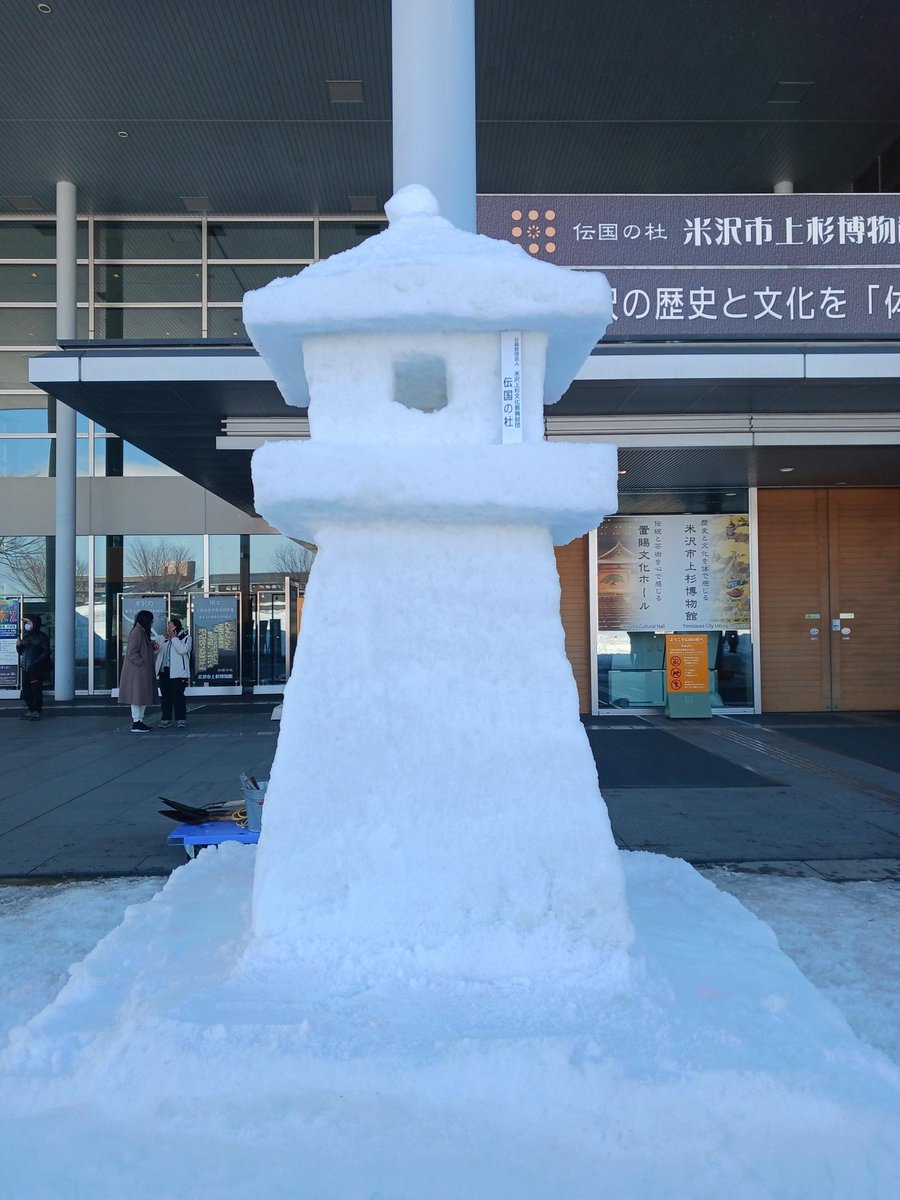 当館入口にも雪灯篭を制作しました。
先日踏み固めた雪の「トーフ」が、
気温の高さで傾いてしまい・・・。
熟練の技で傾きを修正して成形し、
無事に完成しました！