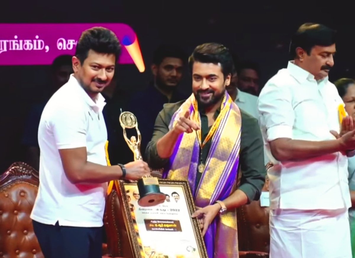 Man is pointing at sudha kongara, saying this award belongs to her as well. 

Golden heart ♥️