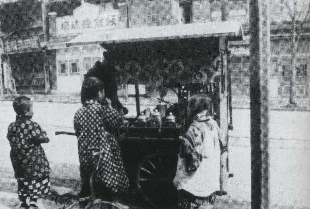 屋台という事で、これは昭和6年（1931年）のどんどん焼き屋です。
どんどん焼きというのは小麦粉にいろんな具材を混ぜて焼きソースをかけたもので、東京におけるお好み焼きの元祖です。2枚目は当時のどんどん焼き屋台。
今のお好み焼きよりも小さくその分安価（今の150-200円ぐらい）で売ってました。