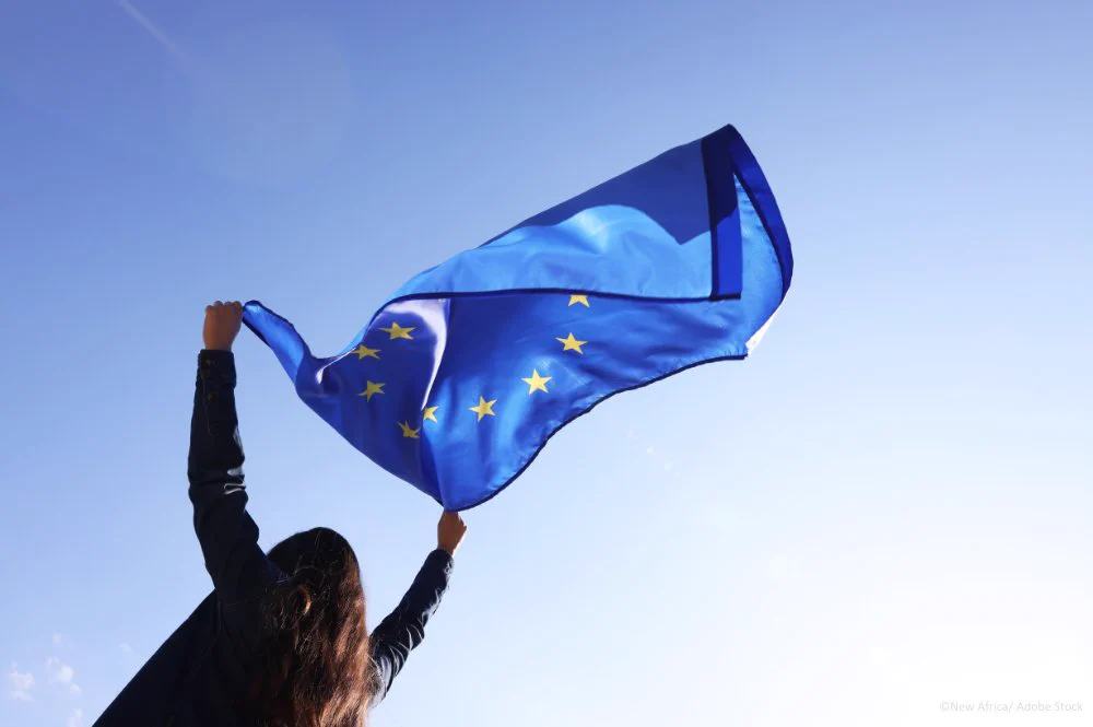 Woman holding European Union flag against blue sky