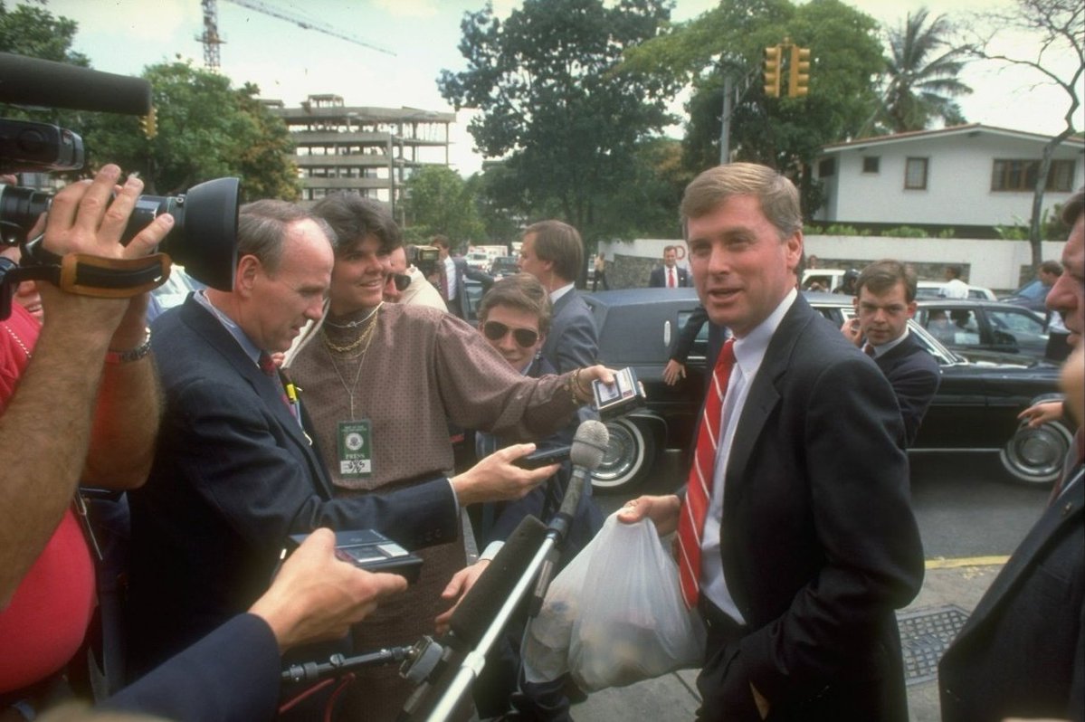 CARACAS, VENEZUELA, 1989. Dan Quayle, Vicepresidente de los Estados Unidos, se detiene para charlar con la prensa, acompañado por un contingente de agentes del servicio secreto, mientras pasea por las calles de la capital venezolana.