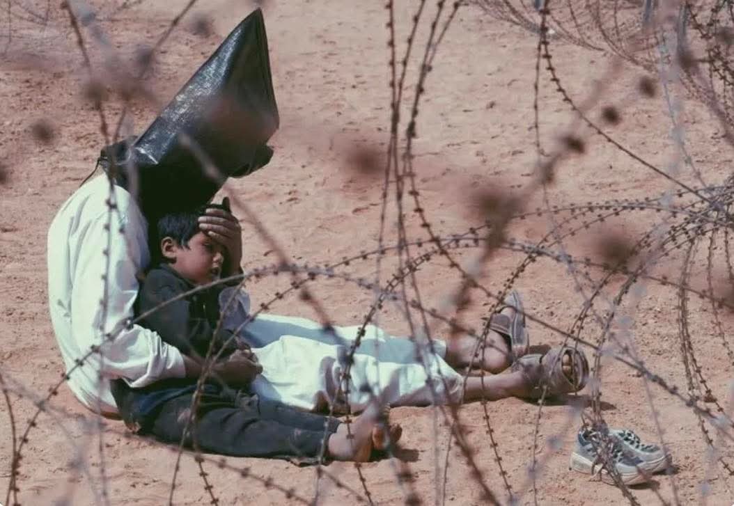 Prisioneiro de guerra iraquiano consolando seu filho de 4 anos em Najaf, Iraque, 31 de março de 2003. 🇮🇶🇺🇸

A foto ganhou o Prêmio Pulitzer...

A fotografia captura um prisioneiro de guerra iraquiano sentado no chão, com a cabeça coberta por um capuz preto, colocando