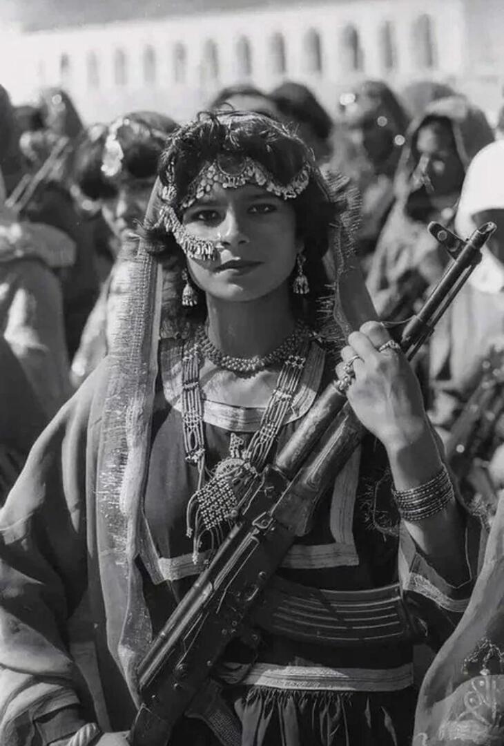 A n Afghan communist revolutionary dressed in traditional clothing and holding an AK-47, in Kabul in 1984.