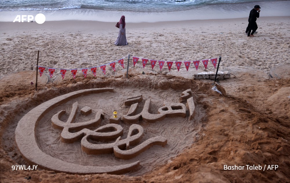 AFPar's tweet photo. عشية بدء شهر الصوم، رسم الفنان الفلسطيني زياد أبو جراد عبارة "أهلاً رمضان" بخط مزخرف على رمال الشاطئ في دير البلح وسط قطاع #غزة، تحت أنظار أطفال المخيم المجاور المكتظ بالنازحين. ويوضح إنه أراد بذلك "القول للعالم كله ما زلنا بخير، وإن شاء الله يكون #رمضان هذا بلا حرب ولا قصف" للمرة الأولى منذ ثلاثة أعوام.

📸 @Bashartaleb / #فرانس_برس