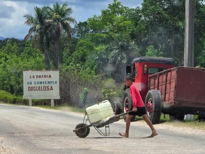 Si hubiese un concurso de fotos ahora mismo, esta se llevaría uno de los mejores premios.

A lo lejos, la consigna de siempre: «La patria os contempla orgullosa». En el centro, un menor de edad, descalzo, cargando lo que parece agua. Da igual. Un reflejo de la sociedad cubana,