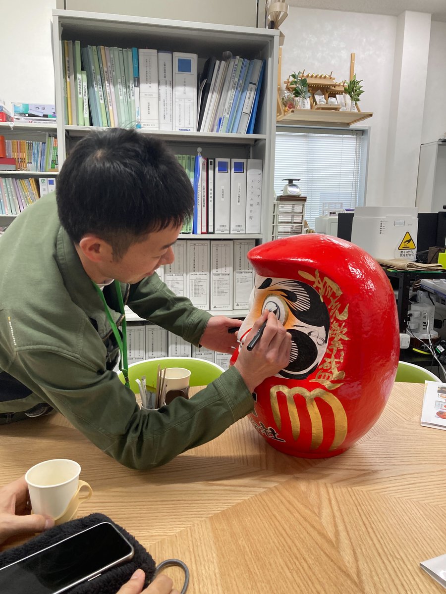 bptofficial2015's tweet photo. 2月19日、縁起の良い甲子（きのえね）の日に、BPTダルマの目入れを行いました!
代表 北角、専務 西川、取締役 福井を中心に、社員一同で心を込めて実施しました😊
ダルマは1年間発電所に鎮座し、事業の発展と安定稼働を見守ります。
来年は祈願成就の節目として、もう一方の目入れを行う予定です✨ https://t.co/k6dBKly4QF