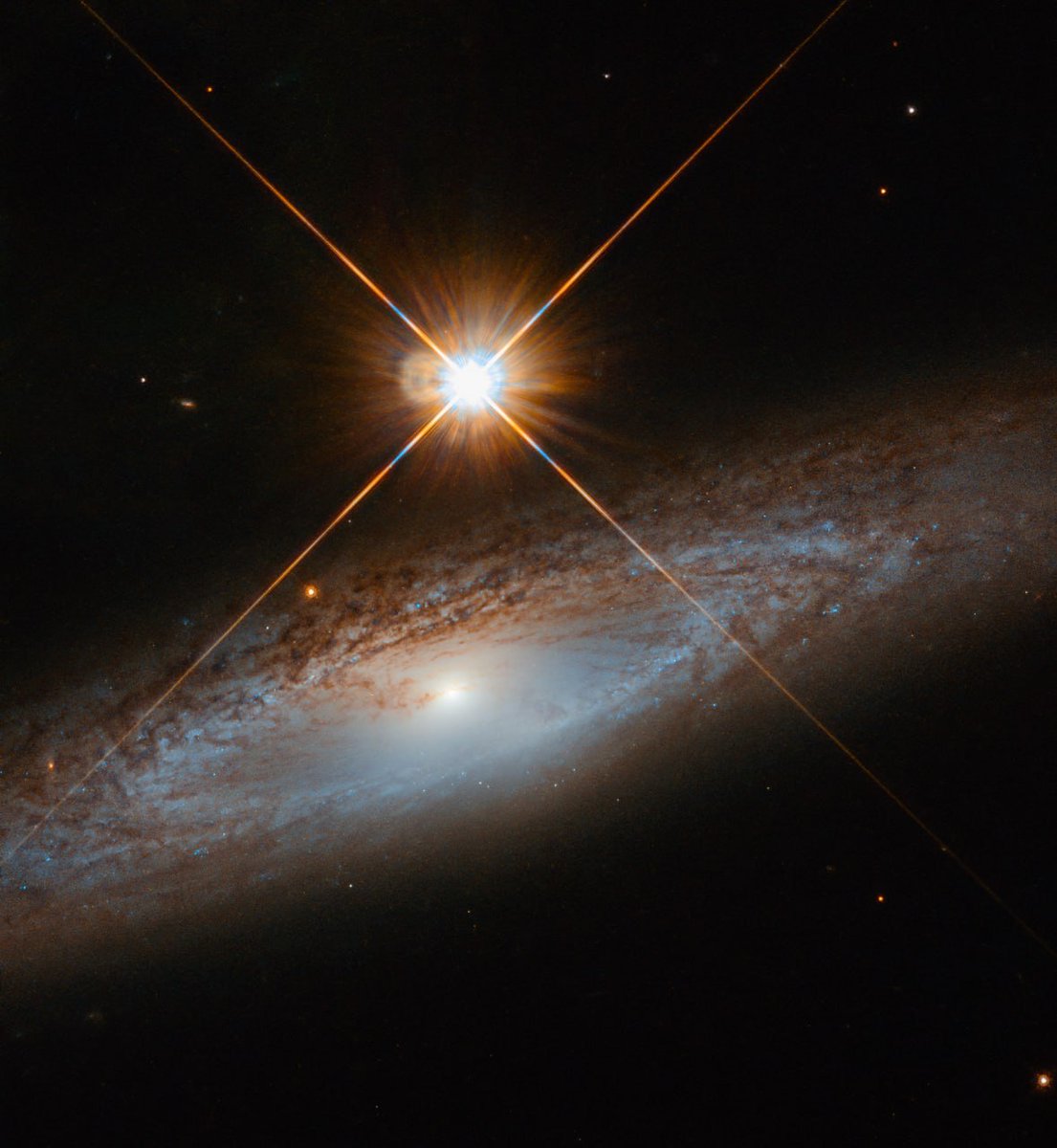 This Hubble image shows the spiral galaxy UGC 3855, located 180 million light-years from the Sun. The brightly shining star in the frame is much closer to us, but it creates the illusion of being enormous and looming over the galaxy.