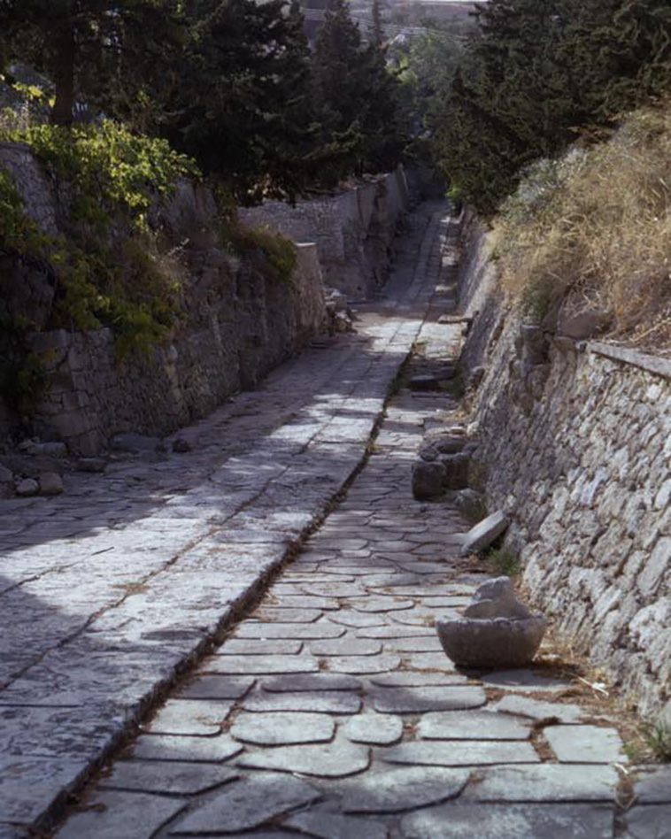 archpng's tweet photo. Not a movie set—this is the Minoan “Royal Road” at Knossos, paved nearly 4,000 years ago. 

One of Europe’s oldest walkable streets, it was laid as early as the early 19th century BC, with stone paving and drainage still surviving in short stretches—so you’re literally stepping onto Bronze Age infrastructure.