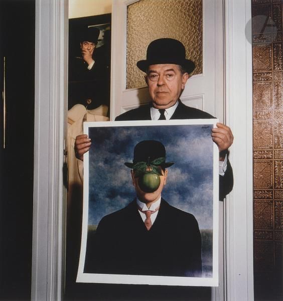 René Magritte holding his painting "The Son of Man" ("Le fils de l'homme"), 1964.