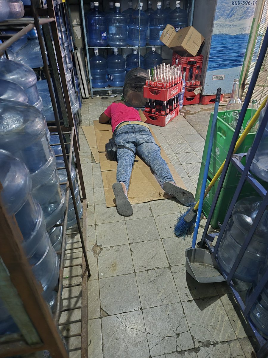 Vine al Carnaval de Santo Domingo en el Malecón, entré a un colmado solo para usar el baño y me topé con esta escena brutal. Allí reposa su almuerzo un trabajador que vive en condiciones indignas: tirado en el piso sobre cartón, rodeado de botellones y cajas, sin un espacio