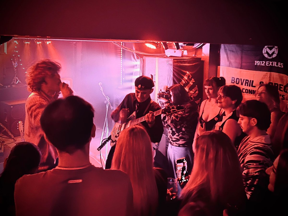 1912Exiles's tweet photo. An absolute privilege to watch local band Maeve play their first headline gig on Friday night at The Pit - especially as they chose to have the 1912 Exiles "Bovril" flag as part of their backdrop!

Check them out, their new single Behind Your Smile is lush.

#ncafc 🧡🖤 https://t.co/UJYaF8kFzx