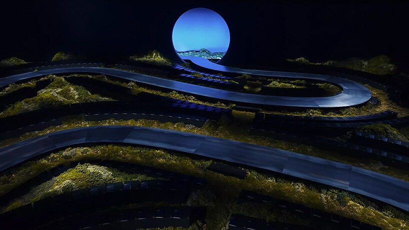 designboom's tweet image. #hermes stages a twilight landscape for its women’s 2026 show at #paris fashion week

for its FW26 presentation, hermes transforms the runway into a scenographic landscape: a winding path cutting through a dim terrain of moss, low vegetation, and earthy textures.

the serpentine