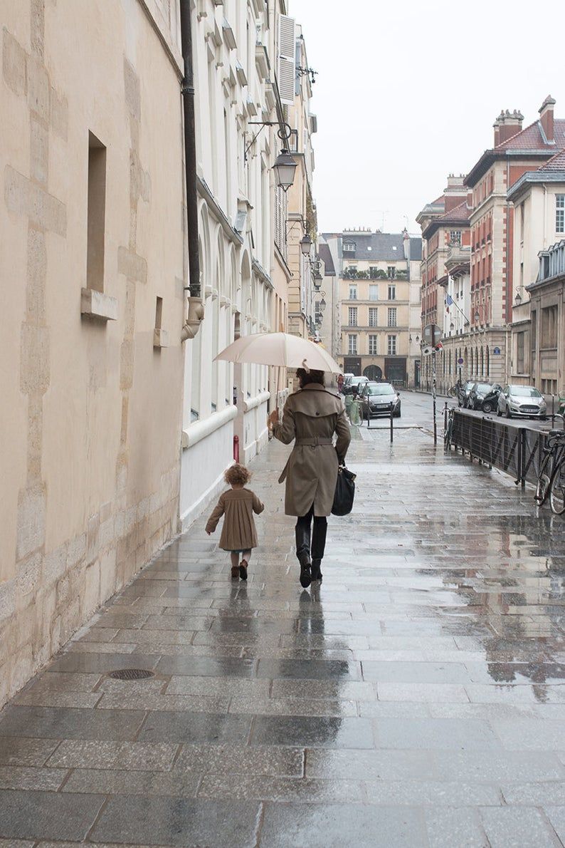 Mother and daughter on a Paris street in the rain.