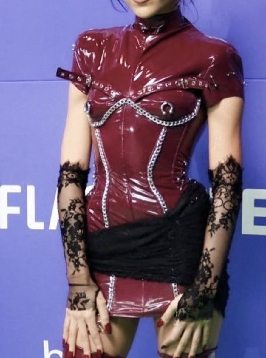 Diseñador: Vanebon (custom)
Evento: MTV MIAW 2024
Estilo: Vestido corset de látex burdeos con cadenas metálicas, guantes y mini falda de encaje Chantilly, cada cadena y piercing de las medias fue cosido a mano

Precio estimado: $4,000 – $8,000 USD (al ser custom couture).