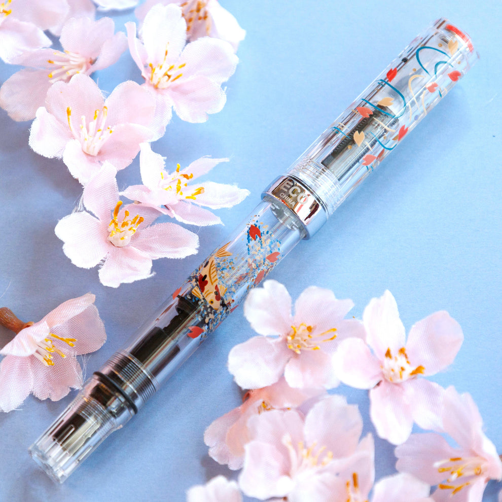 桜の季節を目前にして
今年も美しい桜の万年筆が届きました🌸

〈花の浮橋・錦彩〉
水面に見立てたTWSBI ECOクリアの軸には桜の花びらが舞い降りて、
まさにそこは「花の浮き橋」
その浮き橋に春の訪れを感じたのか
優雅にそしてたおやかに泳ぐ錦鯉
泳ぐ宝石ともいわれる錦鯉、「錦彩（きんさい）」は