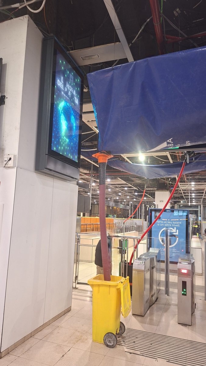 Estació de Sants, un gran recollidor d'aigües sobre les màquines cancel·ladores. Alta tecnologia, el desaigua fet amb un con de trànsit, un tub i un cubell de ♻️ i molta cinta americana. La NASA ja està buscant a qui ho ha fet per enviar-lo a la ISS.