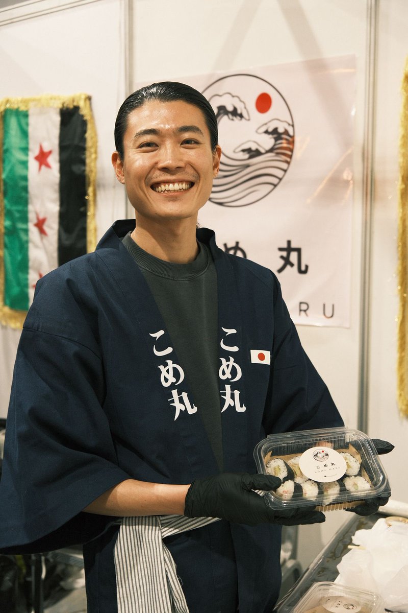 SSJ__official's tweet photo. 【日本人運営のシリア初の日本料理店「こめ丸」開店のお知らせ】
この度、SSJ理事長 山田一竹（@IcchikuYamada）が、ダマスカスに日本料理店「こめ丸」を開店。SSJの活動とは完全に独立した個人事業として運営されますが、山田本人の強い希望により、収益の一部がSSJの活動へ継続的に寄付されます。

シリアにおいて日本人が経営する初の日本料理店となる「こめ丸」は、山田が愛する二つの故郷、日本とシリアを食と文化で繋ぎ、苦難を乗り越えてきたシリア社会の再生をささやかに支える新たな取り組みです。

山田は2014年以降、自身の人生をシリア革命と抑圧されてきたシリアの人々に捧げ、NPO法人Stand with Syria Japanを設立し活動を牽引してきました。研究者としてもアサド政権による絶滅収容所（刑務所）システム、組織的拷問、強制失踪の実態を追及し、犠牲者家族やサバイバーの正義の実現のために尽力してきました。その信念と使命は今も変わることはありません。

2024年12月、シリアは半世紀に及ぶアサド独裁政権から解放されました。山田はこの歴史的転換を受けダマスカスへの完全移住を決断し、自由となったシリアの地から復興と再建、そして正義の実現のために尽力していくことを誓いました。

シリアで生活を始める中で山田の心に芽生えたのは、日本とシリアという愛する二つの故郷を食で繋ぎ、想像を絶する苦難を乗り越えたシリアの人々が尊厳を感じながら過ごせる空間をつくりたいという小さな願いでした。その思いを形にしたのが、日本とシリアを結ぶ日本料理店「こめ丸」です。

こめ丸のスペシャリティとなるのは、日本の家庭料理。特に巻き寿司とおにぎりは、祖母から伝授されたレシピとのこと。北海道で日本料理店を営んでいた祖父母の味を受け継ぎ、山田は心から愛するシリアの人々へ、日本の温かな味を届けます。そのほかにも、日本の親しみ深い料理がメニューを彩ります。

また、こめ丸は単なるレストランではなく、シリアの人々が安心してくつろげる「家」のような空間を目指しています。美味しい料理と温かな記憶、家族のような笑い声があふれる場所。それが「こめ丸」です。

グランドオープンに先立ち、2025年2月5日から16日に開催され、初日に約20万人が来場したダマスカス国際ブックフェアにおいて、期間限定のポップアップ店舗としてデビューしました。シリア文化省の全面的な協力のもと営業し、連日多くの来場者で賑わい全日完売の盛況となりました。この取り組みはシリア国内メディアのみならずアルジャジーラなど国際メディアでも大々的に紹介されています。

ポップアップ終了後、山田はメディアに次のように語りました。

「自分が作った日本料理を通して多くのシリア人が笑顔になってくれたのを見て、私は初めて喜びが裏切りではなく、私たちが勝ち取った権利なのだと感じました。この14年間、シリアが虐殺と破壊に引き裂かれる中で私たちは喜びや幸せという感情さえ押し殺してきました。しかし今、解放されたシリアで初めて喜びを分かち合うことができます。こめ丸の料理は単なる料理ではありません。それは愛であり、思い出であり、帰属意識であり、尊厳の回復そのものです。私はこの場所を通してシリアの人々に伝えたい。あなたたちは誰よりも喜びと尊厳を感じながら生きる権利があるのだと。生き延びるのではなく、生きることの喜びを感じてほしい。こめ丸は私の第二の故郷シリアへの最大の愛情表現です。」

改めてお伝えしますが、「こめ丸」はSSJの事業ではなく山田個人による完全に独立したプロジェクトです。しかし山田の希望により、収益の一部はSSJの活動へ継続的に寄付されます。これらの資金は強制収容所サバイバー支援、強制失踪者家族支援、教育施設の再建など、SSJが展開する人道・人権プロジェクトに充てられます。

山田は今後もSSJ理事長としてシリアにおける正義の追求と国の再建のために活動を続け、ジェノサイド研究者としての調査研究も継続していきます。そして何より、山田にとってシリアとの歩みはこれからも人生の中心であり続けます。こめ丸はその歩みから離れたものではなく、むしろシリアへの愛と連帯を別の形で表現した、もう一つの社会的プロジェクトです。

現在シリア全土には日本外務省による渡航危険情報レベル4が発出されていますが、いつの日か日本の皆様が安心してシリアを訪れることができる日が来ることを心から願っています。その際には、日本とシリアの連帯から生まれた場所であり、両国を結ぶ新たな架け橋となる「こめ丸」にもぜひお立ち寄りください。

NPO法人Stand with Syria Japan
職員一同