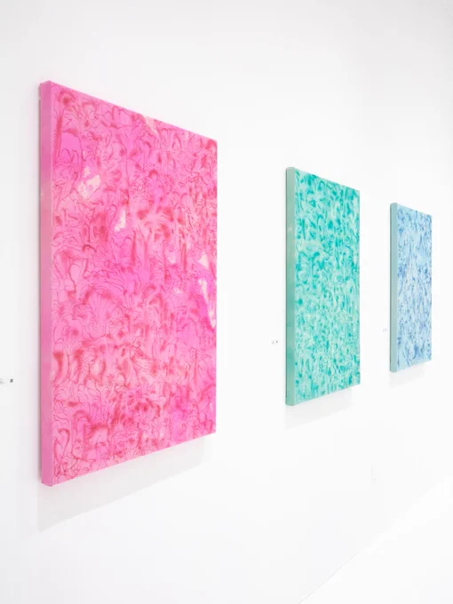 Abstract floral compositions in magenta, green amethyst, and blue hanging on a white gallery wall.