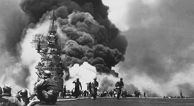 500kg爆弾を抱えた2機の零戦によって特攻攻撃され炎上する空母バンカーヒル。写真は武功を遂げた小川清少尉と安則盛三中尉、艦内の消火活動で焼死した乗員たちの遺体。小川少尉は突入で甲板に放り出され亡くなったが遺体は目立った傷もなかったという。戦後遺品が遺族へ返還されたという。 