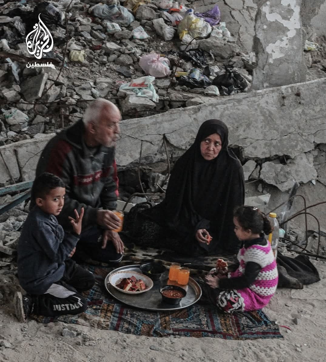 عائلة فلسطينية تفطر بين أنقاض مدرسة دمرها الاحتلال خلال حرب الإبادة على قطاع غزة.