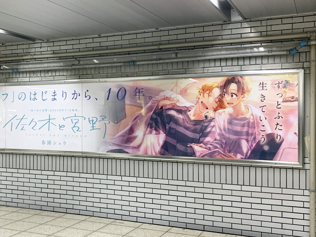 JR池袋駅北口改札外 右手に #佐々木と宮野 の10周年＆最新11巻発売を記念したロングポスターが掲出されています✨
10周年に突入したふたりの物語を見守るようなカットが掲載されたクリエイティブになっています💖
x.com/SasakiANDMiyan…