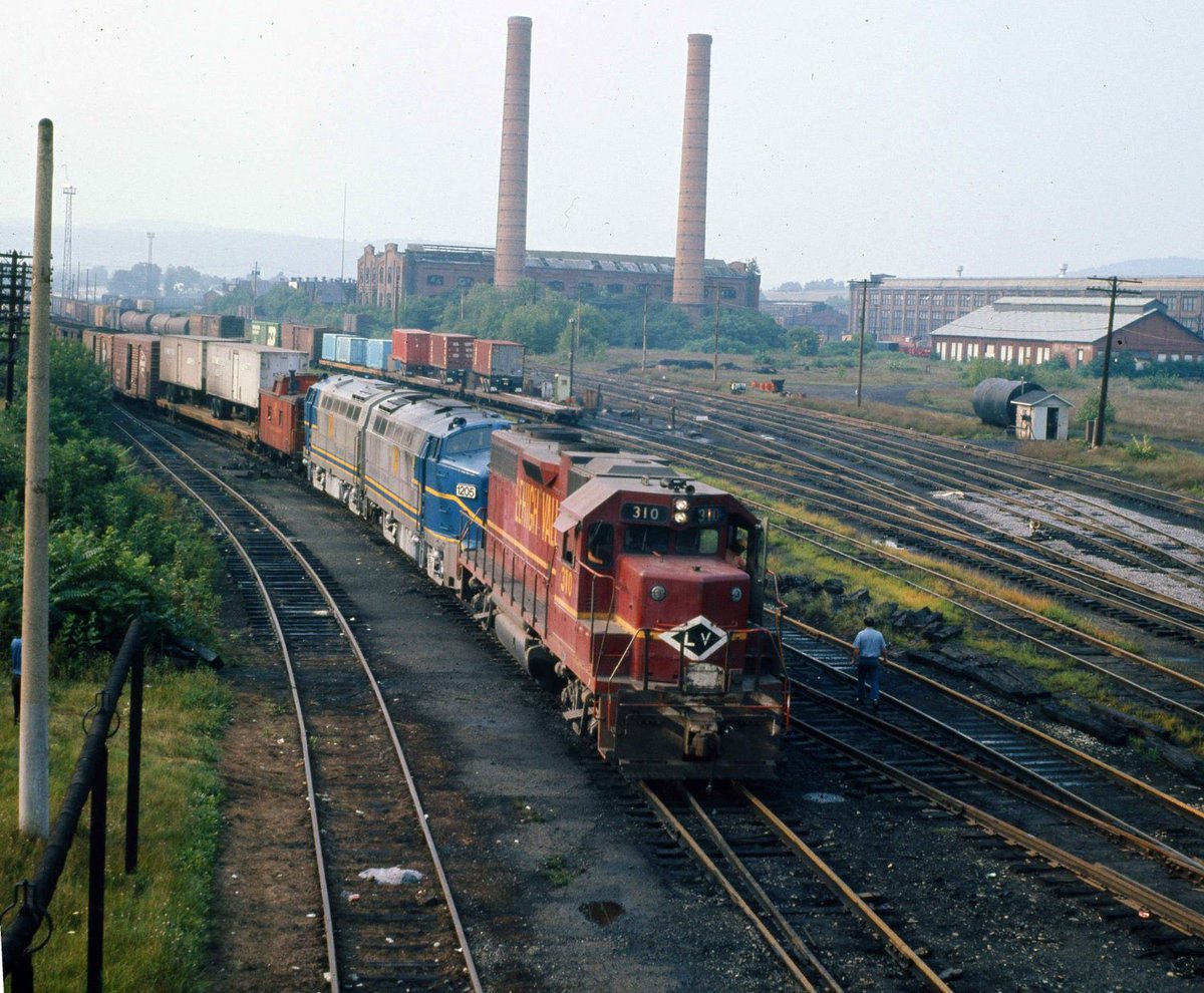 Lehigh Valley GP38AC #310 pulls the Delaware &amp; Hudson's pair of RF16 "Sharks" and their train into the LV's terminal at Sayre, Pennsylvania in August of 1975. Since the D&amp;H freight had operated over the Erie Lackawanna's main line they arrived at the yard's west end and were thus