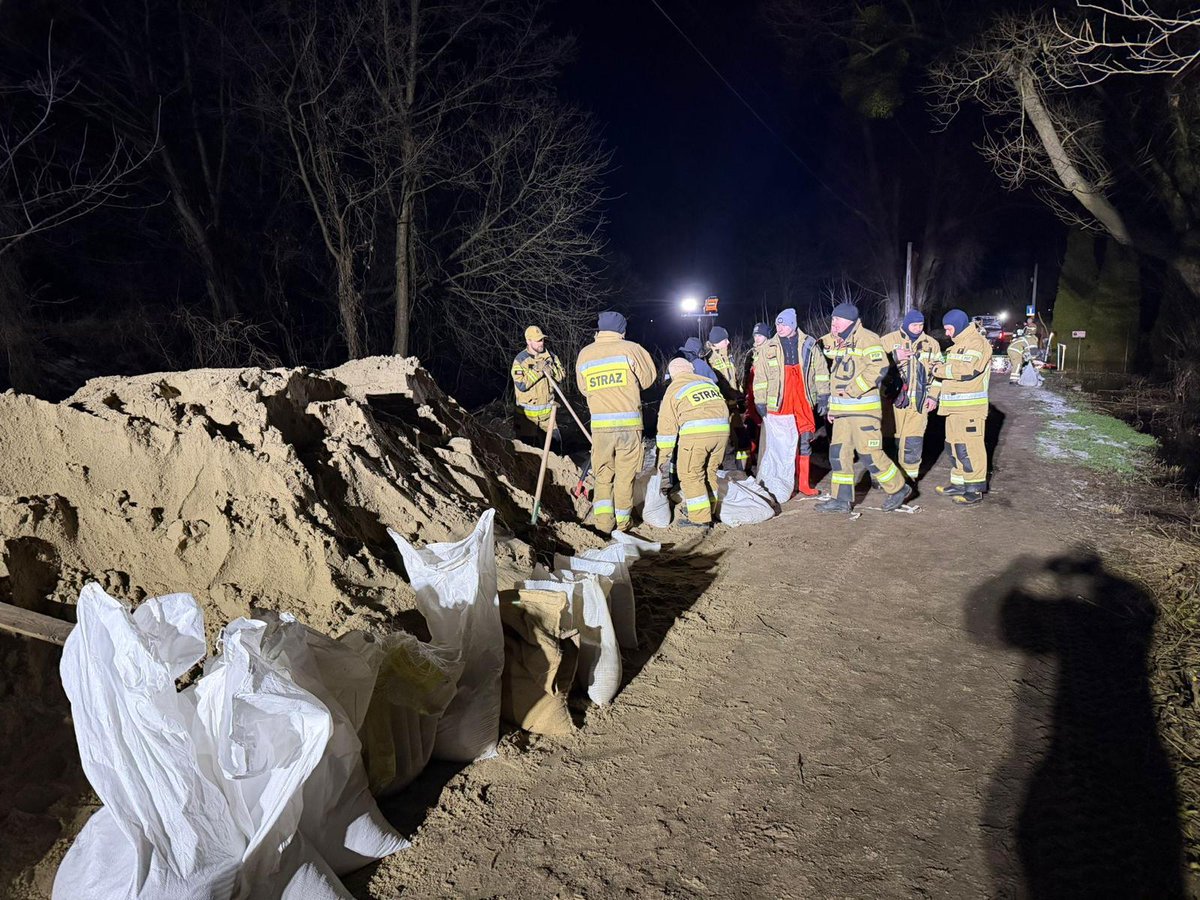 MSWiA_GOV_PL's tweet photo. 🚨 Sytuacja na rzece Wkra w Błędowie (gm. Pomiechówek): rzeka wystąpiła z koryta z powodu zatoru lodowego. Poziom wody stabilny, na wodowskazie Borkowo woda opada. 

Na miejscu był minister @MKierwinski, wojewoda mazowiecki @M_Frankowski. Z żywiołem walczy 18 zastępów Straży Pożarnej @KMazowieckim @Kw_PSP_Wwa, 65 strażaków.  

Służby ułożyły worki i rękawy z piaskiem, a teraz ukierunkowują rozlewisko do koryta rzeki. Zagrożonych podtopieniem jest ok. 20 posesji (domki letniskowe i całoroczne), zalane 4 garaże.