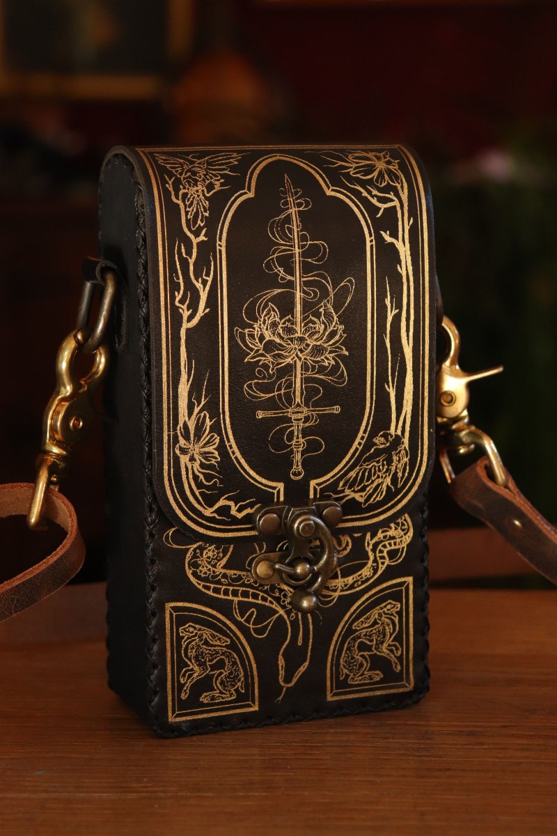 SpeechlessBard's tweet image. Today's the day! 🎉  
The new Festival pouch and Garden Witch illustration releases at 8pm CET. And while the purple leather might be in short supply, we'll do our best to always keep black leather available. Look at that gold inlay ✨ SHINE✨ 
#leathercraft #handbag