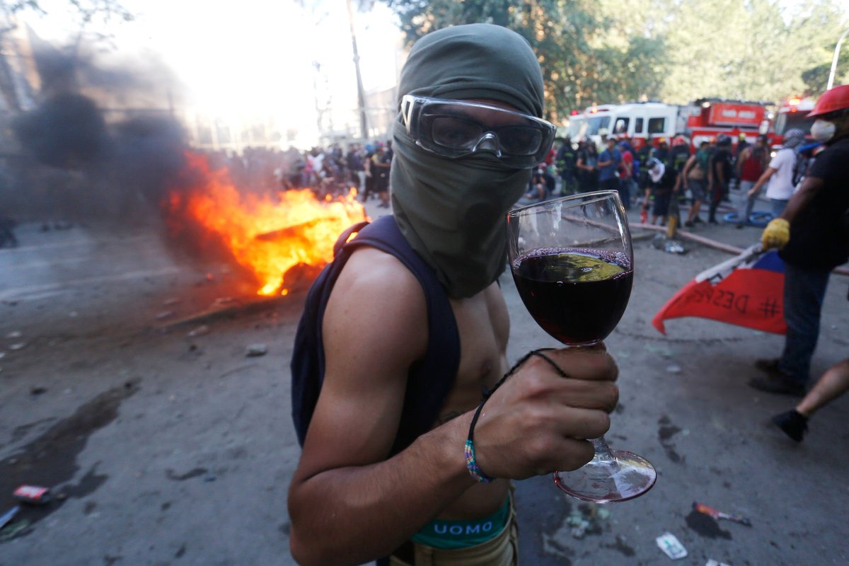 Manifestantes encapuchados celebran el saqueo al sector gastronómico de Plaza Italia el 12 de noviembre de 2019 en Santiago, Chile.